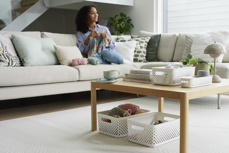 SmartStore Essence Baskets under a living room table, in the background a woman knitting on the couch